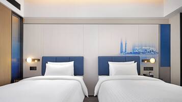 A hotel room with two beds, a cityscape painting on the wall, and a control panel on the nightstand.