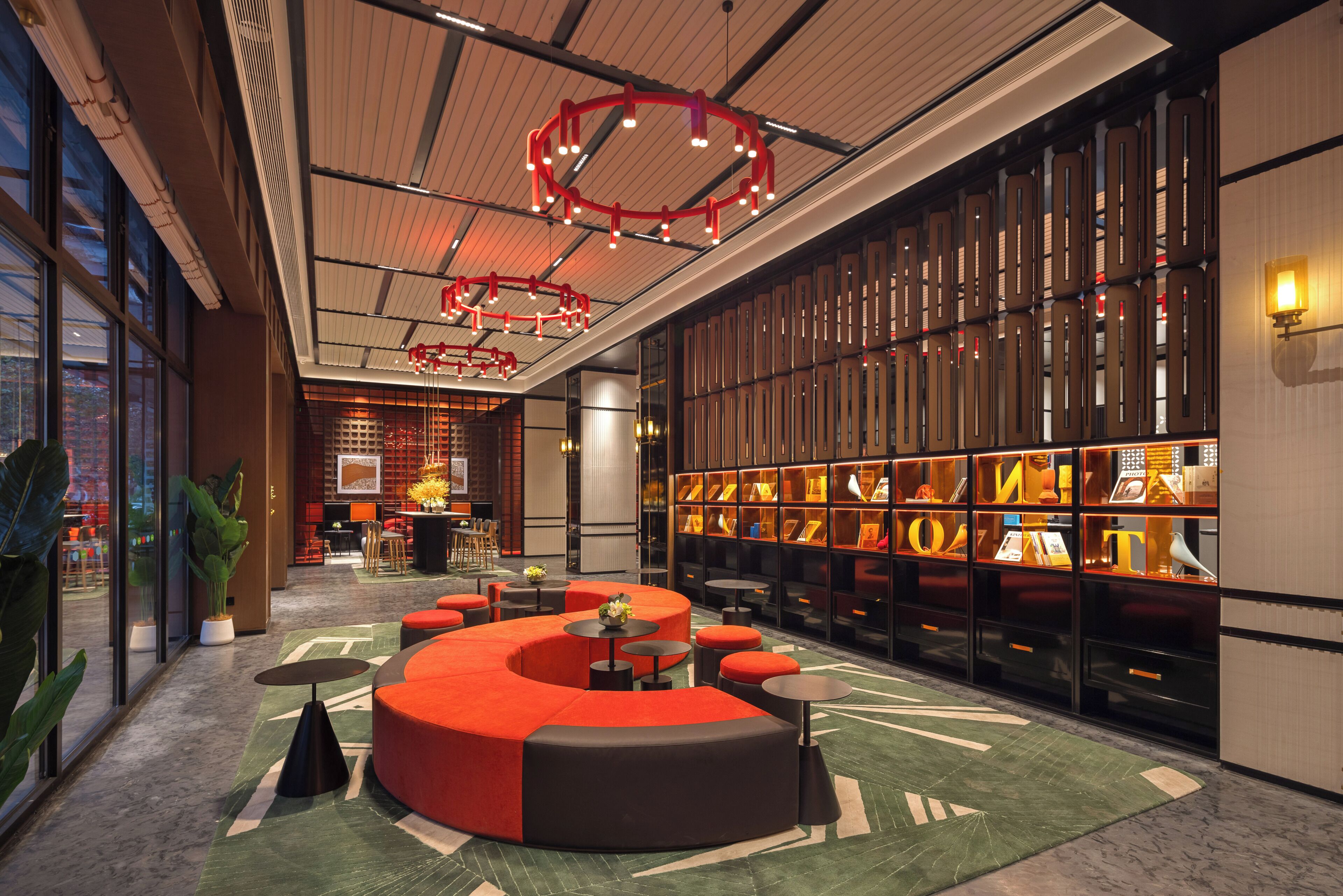 A modern interior with a central seating area, a large bookshelf, and a ceiling with a unique light fixture.