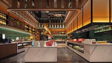 A modern hotel lobby with a central island, a coffee bar, and a variety of amenities.