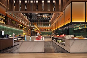 A modern hotel lobby with a central island, a coffee bar, and a variety of amenities.