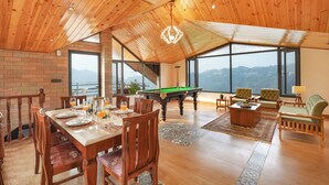 Amplia habitación con mesa de billar, comedor y grandes ventanales con vistas a las montañas.