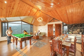Una habitación amplia con mesa de billar, sofá y comedor con vistas.