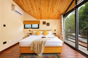 Un dormitorio con una cama grande, techo de madera y vistas a la vegetación.