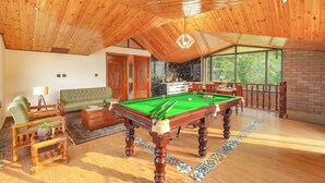 Amplia sala de estar con mesa de billar, sofá y mesa de comedor.