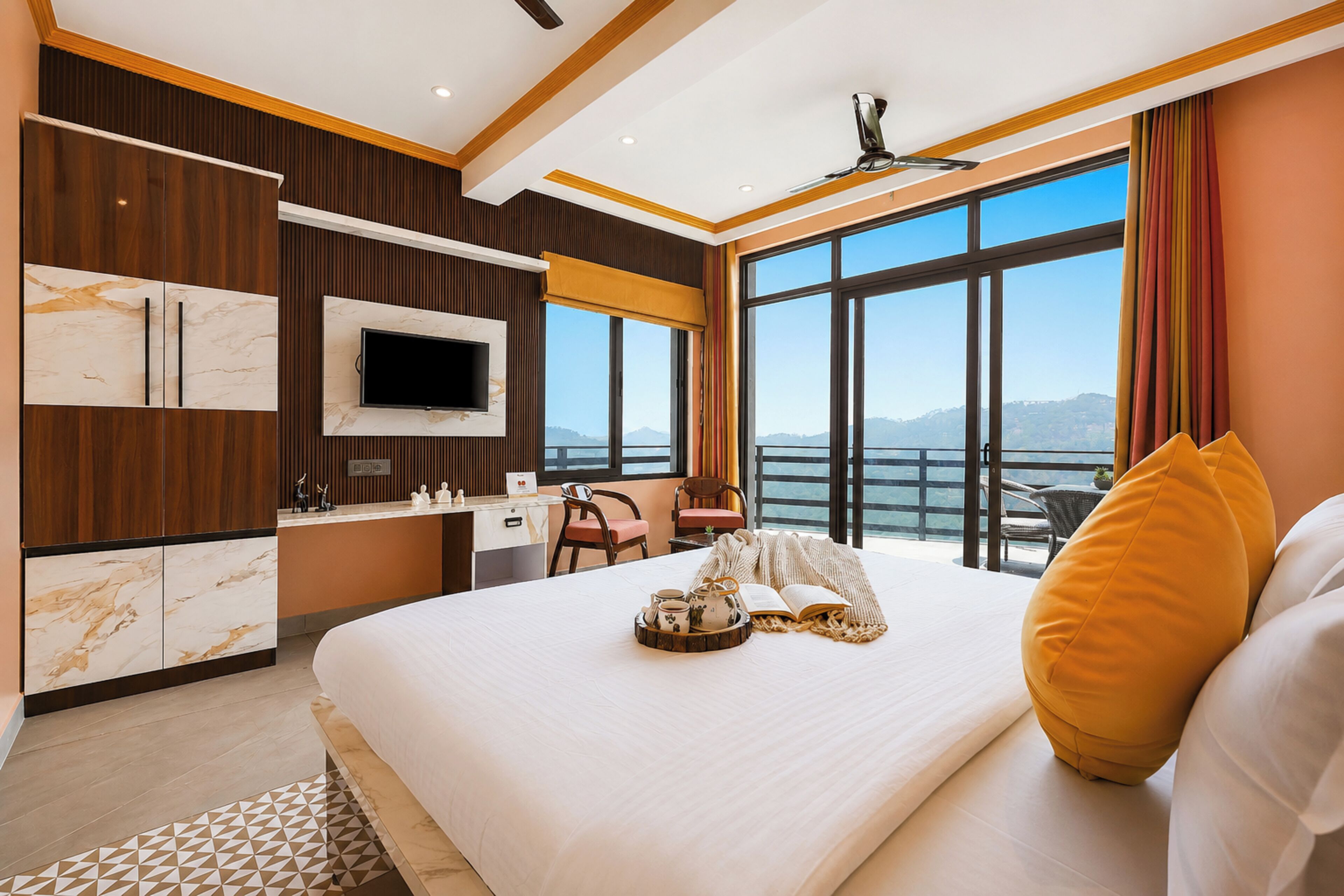 Ein Hotelzimmer mit einem großen Bett, einem Schreibtisch, einem Fernseher und Blick auf die Berge.