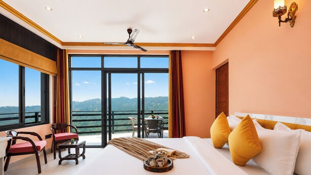 Habitación de hotel con una cama grande, un escritorio y vistas a las montañas.