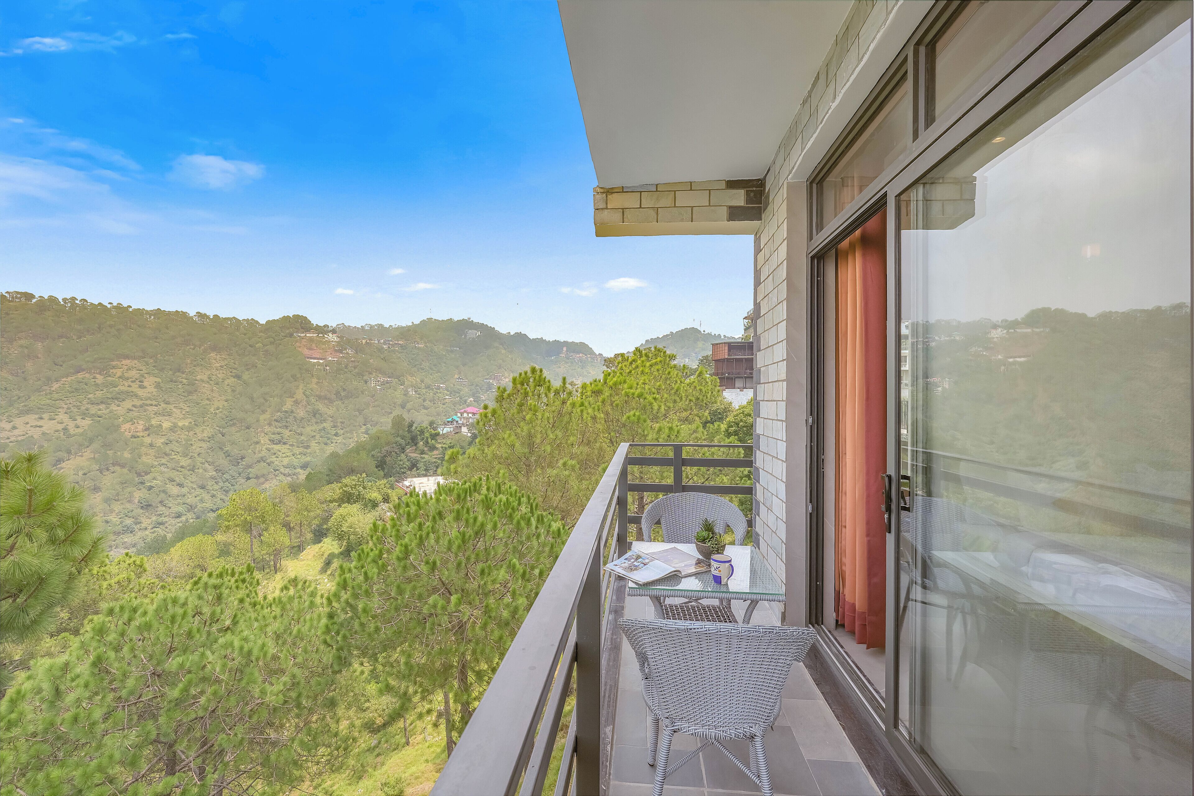 A balcony with a glass door, a chair, and a table with a plant and a mug.