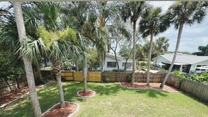 A residential backyard with a wooden fence, a lawn, and several trees. - The Madonna House | Entire Beach Retreat | 6BD 4BA (St. Augustine)