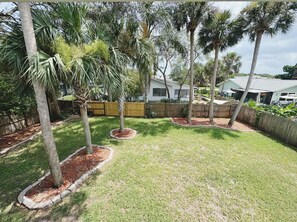 A residential backyard with a wooden fence, a lawn, and several trees. - The Madonna House | Entire Beach Retreat | 6BD 4BA (St. Augustine)