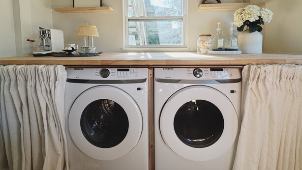 A laundry area with two front-loading washing machines, a window, and a countertop with various items. - The Madonna House | Entire Beach Retreat | 6BD 4BA (St. Augustine)