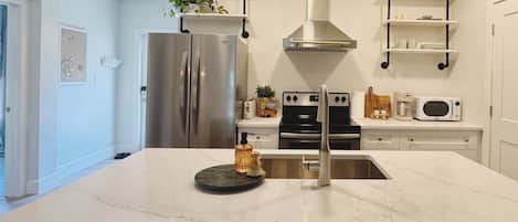 Una cocina moderna con un refrigerador de acero inoxidable, una estufa integrada y un microondas.