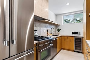 A modern kitchen with stainless steel appliances, wooden cabinets, and a window with a view of the outdoors.