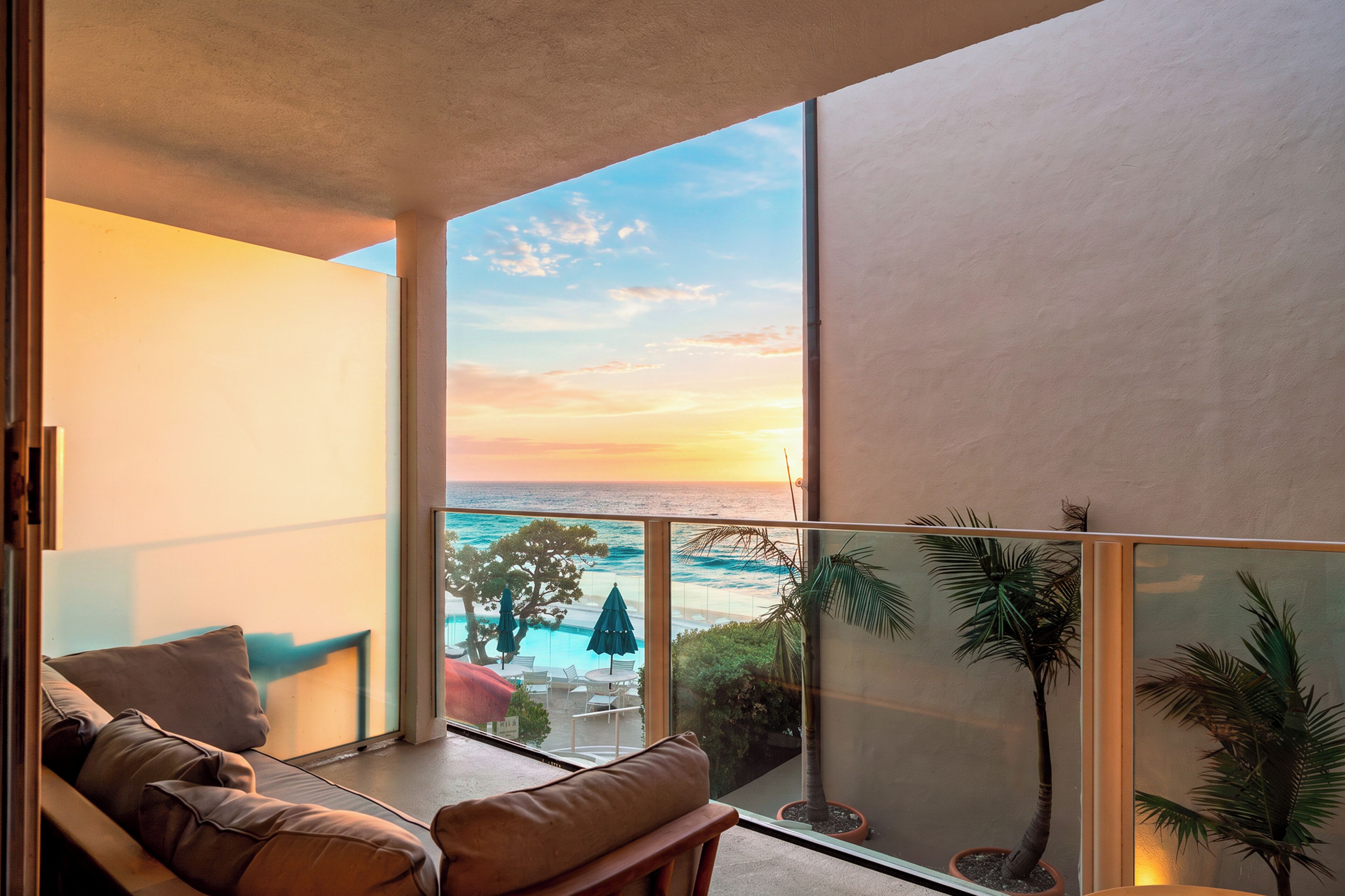 A balcony with a view of the ocean and a pool area.