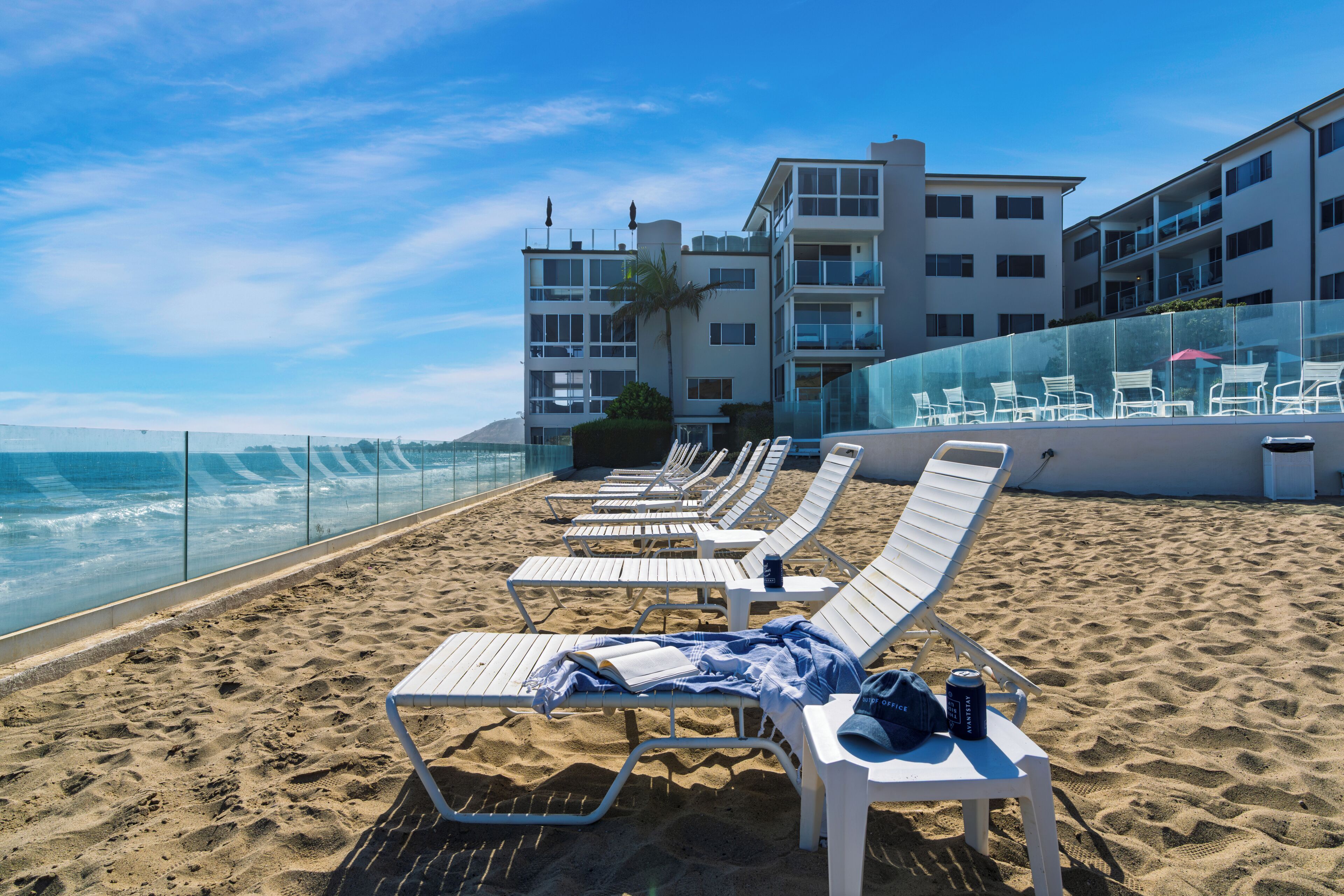 Un hotel frente a la playa con varios balcones, sillas de sol y vistas al océano.