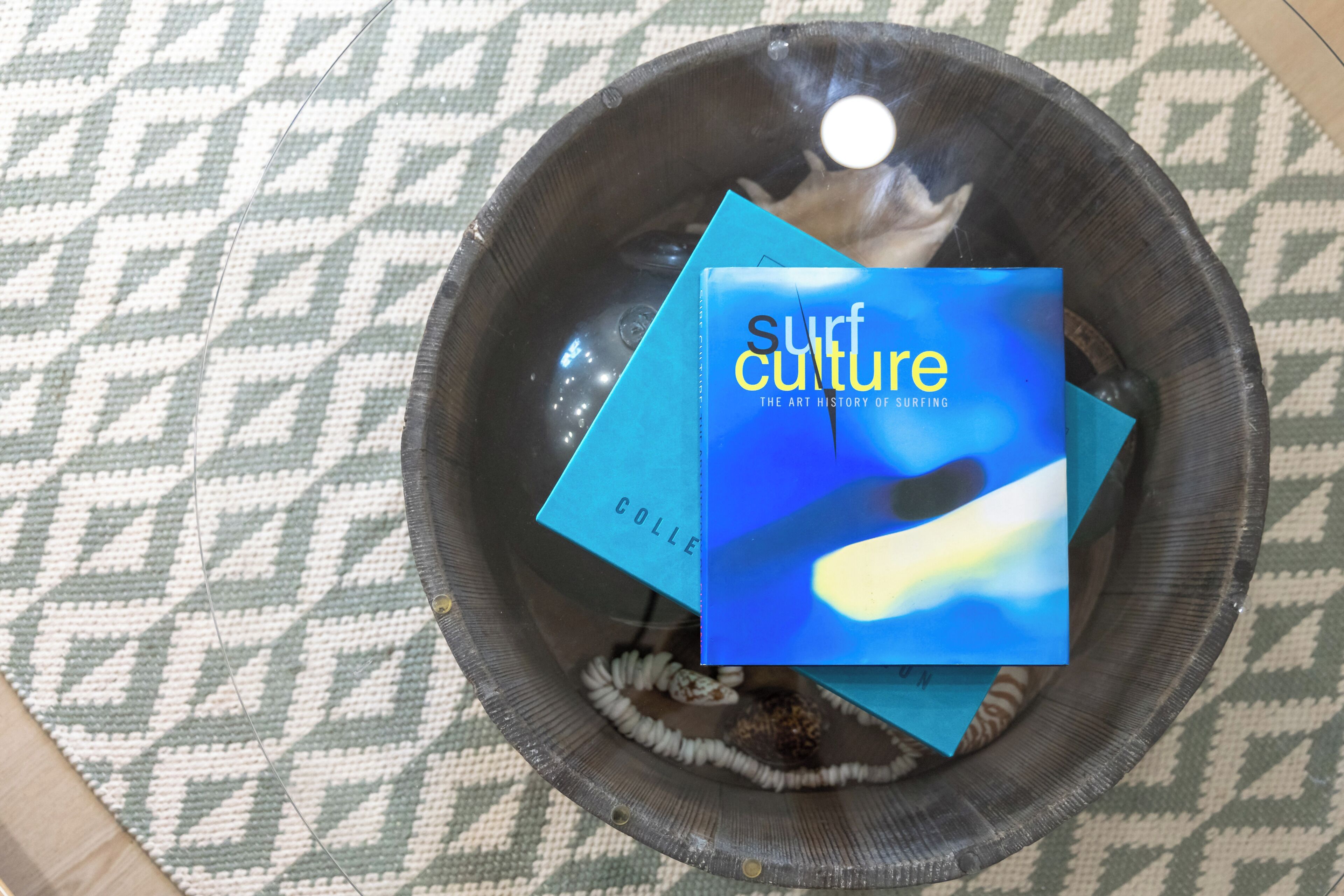 A bowl containing a book titled 'surf culture' and a blue object.