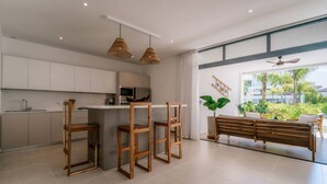 A modern kitchen with white cabinets, a microwave, and a dining area with a bench and chairs. - 2BR Ground Floor Beach Retreat | Partial View (Las Terrenas)