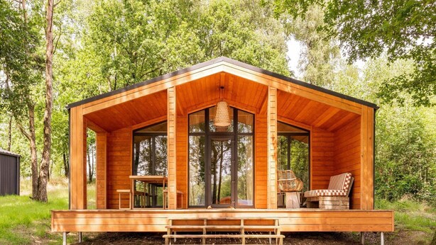 A wooden cabin with a porch, large windows, and a bench. - Premium Waterfront Scandi Lodge (Wilsum)