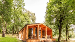 A wooden cabin with a porch, built into a forested area. - Premium Waterfront Scandi Lodge (Wilsum)
