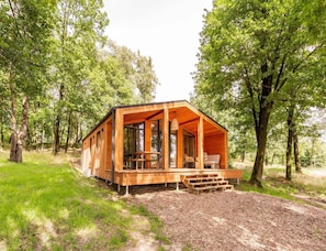 A wooden cabin with a porch, built into a forested area. - Premium Waterfront Scandi Lodge (Wilsum)