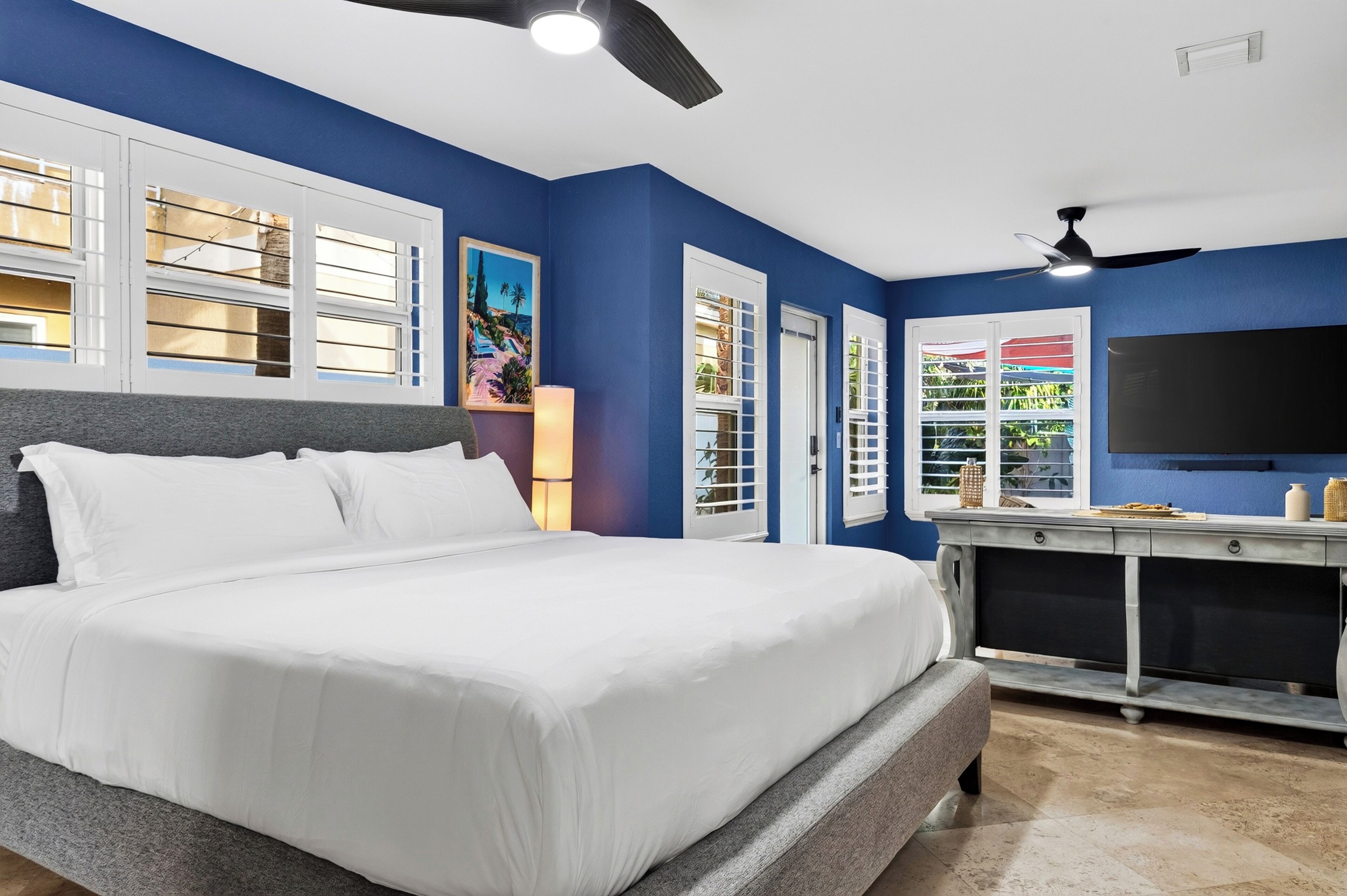 A bedroom with a large bed, a desk, and a television.