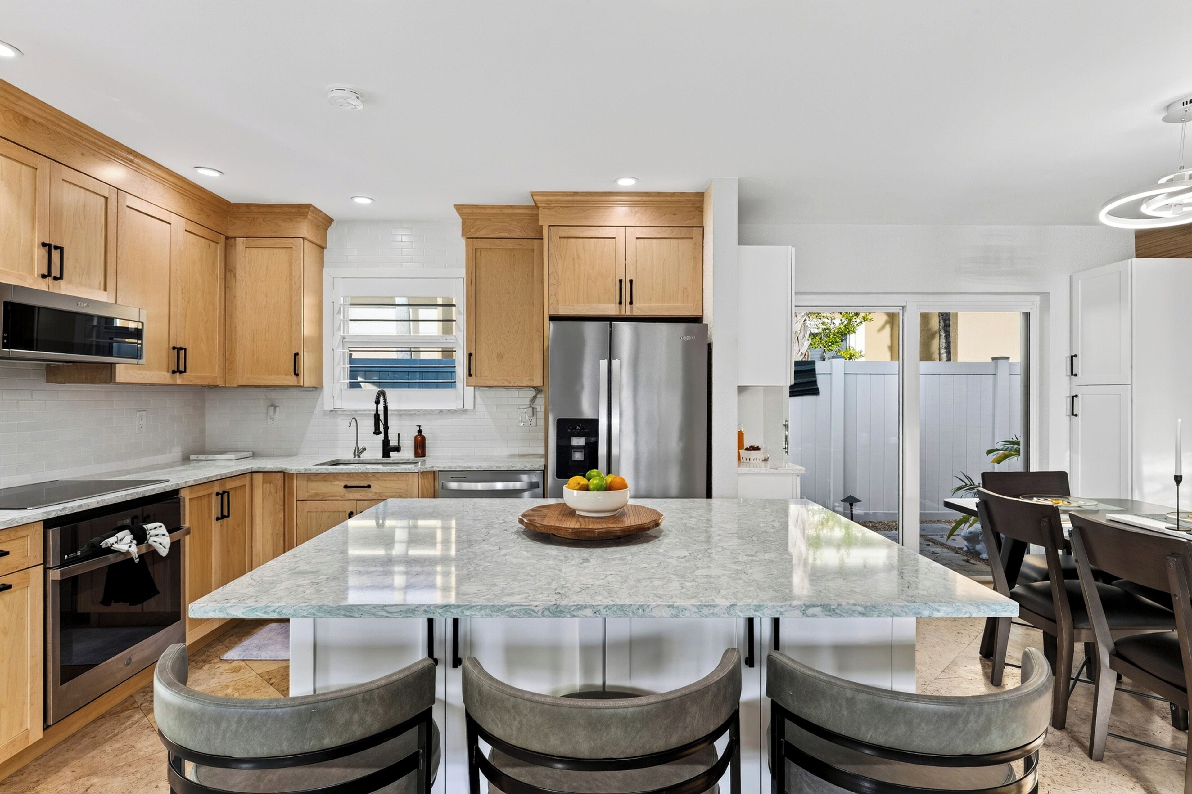 A modern kitchen with a central island, stainless steel appliances, and wooden cabinetry.