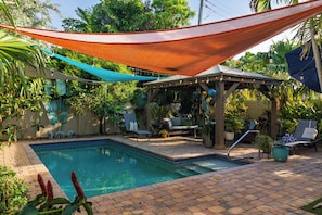 A backyard with a swimming pool, patio furniture, and a covered seating area. - Baby Be Sweet by AvantStay | Pool + Gazebo Lounge | Walk to Dining (Oakland Park)
