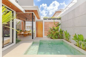A modern outdoor pool area with a dining set and potted plants. - Villa Kartal Altin by Pertama Stay (Badung Regency)