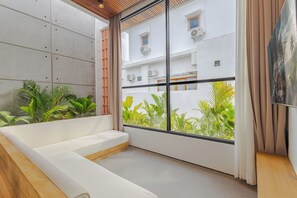 A modern room with a white sofa, a large window with curtains, and a view of greenery outside. - Villa Kartal Altin by Pertama Stay (Badung Regency)