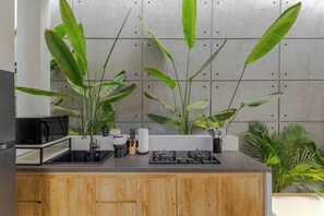 A kitchen with a wooden cabinet, a black countertop, and green plants. - Villa Kartal Altin by Pertama Stay (Badung Regency)