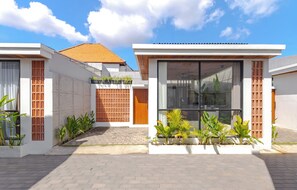 A modern residential building with a tiled roof, large windows, and a paved entrance. - Villa Kartal Altin by Pertama Stay (Badung Regency)