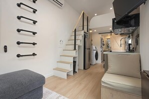 A modern kitchen with a built-in microwave, a washing machine, and a dining area with a sofa and a small table.