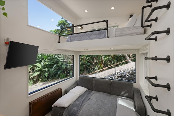 A compact, multi-level room with a bunk bed, a sofa, and a television.