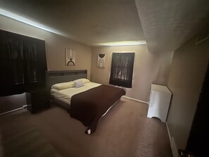 Ein Hotelzimmer mit Bett, Nachttisch, Lampe und einem fensterbepflanzten Fenster.