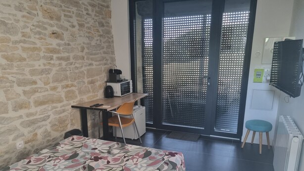 Quarto com cama, escrivaninha, cadeira, radiador e televisão.