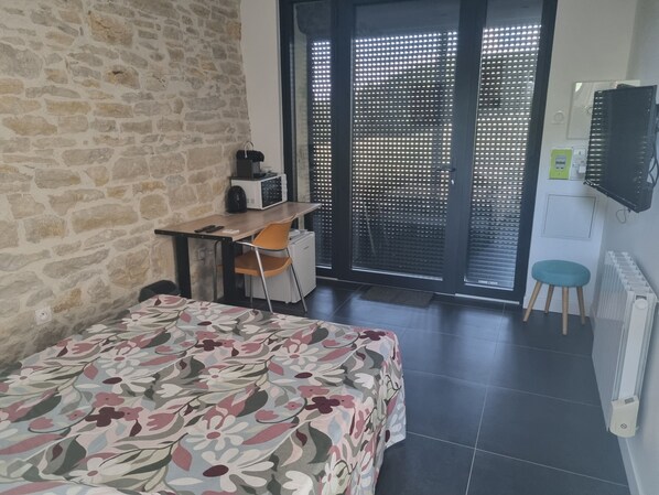 Un dormitorio con cama, escritorio, silla, radiador y televisor.