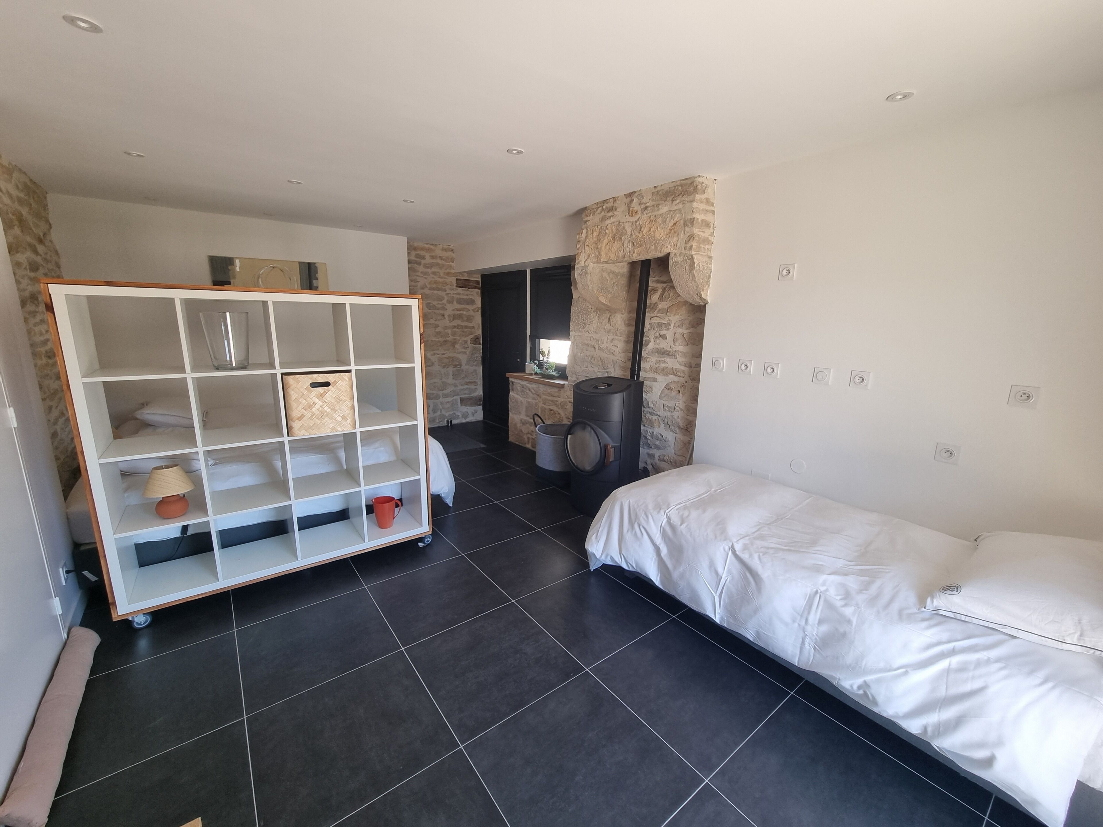 Une chambre moderne comprenant un lit, une armoire intégrée, un mur d’accent en pierre et un lave-linge.