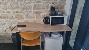 Uma cozinha compacta com micro-ondas, chaleira e pequeno frigorífico.