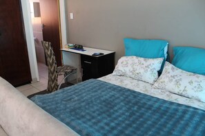 A bedroom with a bed, a desk, and a chair.