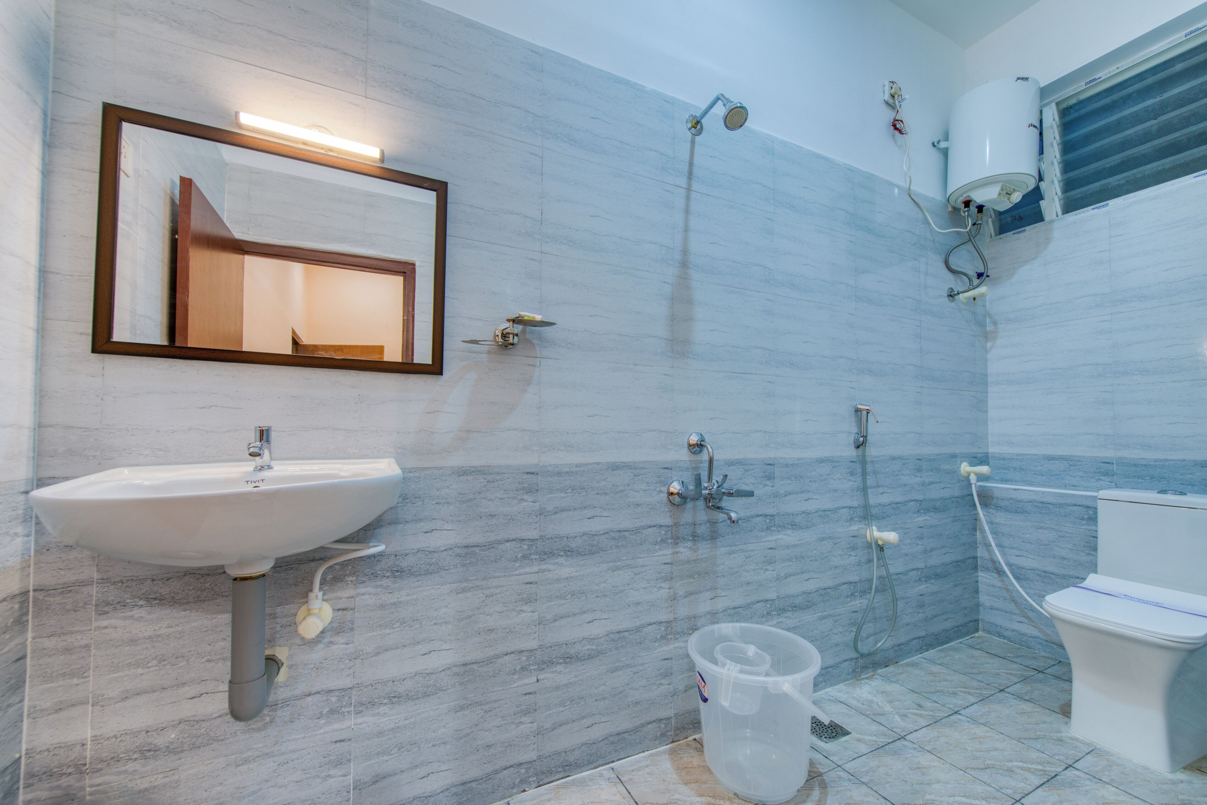 A bathroom with a white sink, a mirror, a shower, and a toilet.