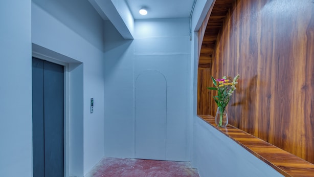 Un pasillo con pared de madera, una puerta blanca y un pequeño florero sobre un alféizar de madera.