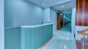 Un  área de recepción moderna con un mostrador curvo, un ventilador de techo y un pasillo que conduce a una puerta de madera.