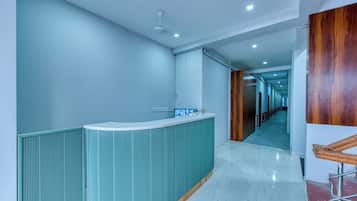 A modern reception area with a curved counter, a ceiling fan, and a hallway leading to a wooden door.