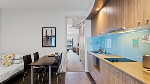 Une cuisine moderne équipée d’un évier, d’un plan de travail et de meubles de rangement en bois. On y trouve également un coin repas avec une table et des chaises, ainsi qu’un lit agrémenté de coussins à motifs floraux.