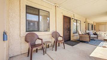 A covered outdoor seating area with wicker furniture, a door, and windows.