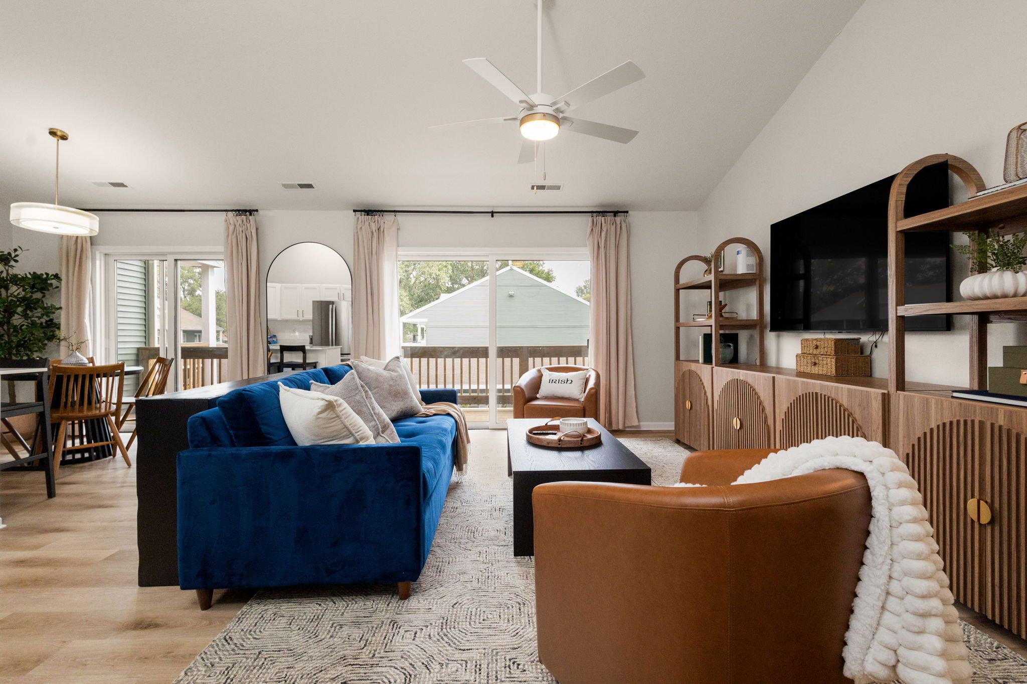 A spacious living room with a blue sofa, a brown armchair, and a wooden entertainment unit.