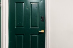 A green door with a keypad lock and a brass handle. - Walk to ND Luxury 2BR/2BA Condo Balcony + Parking (South Bend)