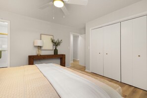 Ein Schlafzimmer mit Bett, Nachttisch, Lampe, Spiegel und Kleiderschrank.