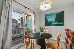 Ein Essbereich mit einem runden Tisch, Holzsesseln, einer Topfpflanze und einem Bild an der Wand.