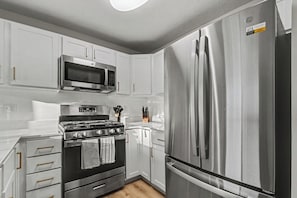 A modern kitchen with stainless steel appliances, white cabinetry, and a built-in oven. - Game Day Luxury | 2B/2BA Condo By ND | Balcony (South Bend)