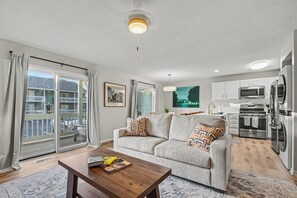 Ein Wohnzimmer mit einer Couch, einem Couchtisch und Blick auf einen Balkon.